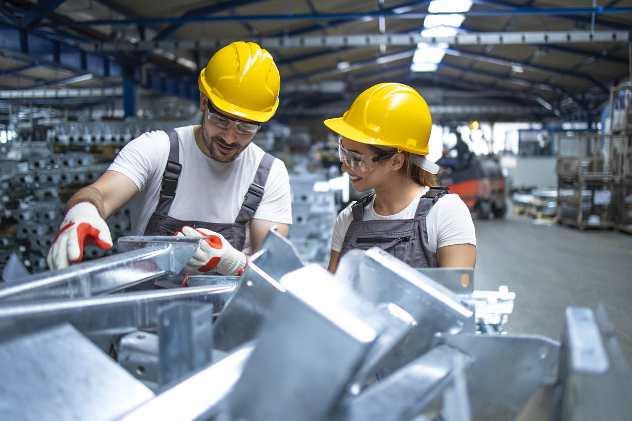 Factory workers checking quality of industrial metal parts.